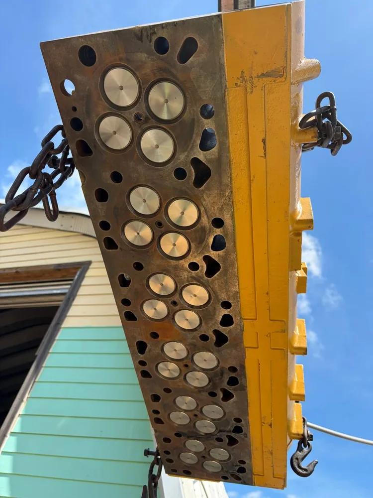 Freshly machined diesel cylinder head rigged on chains