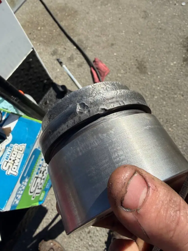 P&C technician holding a machined hydraulic piston during a roadside hydraulic repair