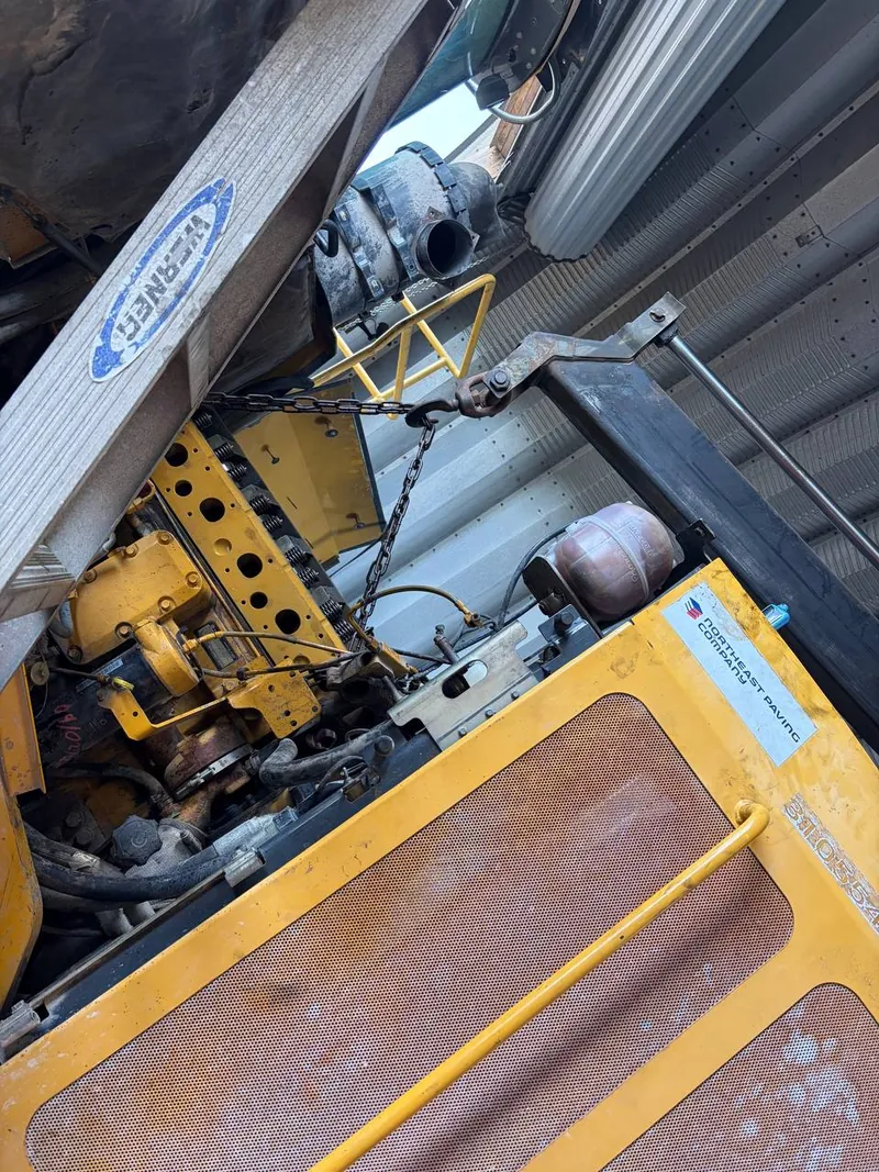 Engine bay of a heavy machine opened up with a chain hoist rigged overhead
