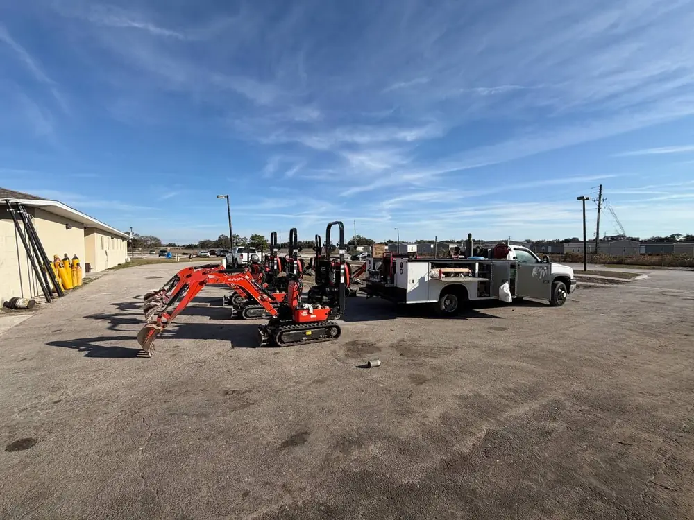 Mini excavators and the P&C service truck staged in a Southwest Florida equipment yard